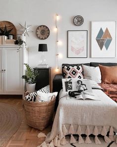 a bedroom with white walls and pictures on the wall next to a bed, wicker basket