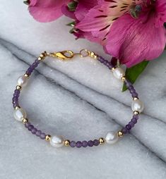 Amethyst and Pearl purple and white bracelet handmade with beautiful 2x3mm Amethyst faceted rondelle gemstones combined with 7x5mm white freshwater pearls and delicate 3mm round gold plated beads. The facets on the Amethysts sparkle beautifully when they catch the light whilst the pearls have a silky lustre.  The bracelet is 19cm long and has a gold plated trigger clasp. If you would rather the bracelet had a Gold or Gold filled clasp please contact me and I will provide a quote for that. It wou Purple Pearl Bracelet, Purple And White Bracelet, Pretty Bracelets Diy, Purple Bracelets Beads, Beaded Jewelry Inspiration, Gemstone Bracelets Ideas, Handmade Jewelry Ideas Necklace, Pearl Bracelet Ideas, Purple Beaded Jewelry