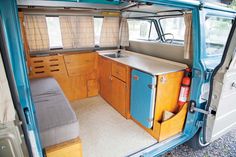 the interior of an old camper van with wood cabinets and blue doors is shown