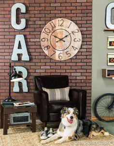 a dog laying on the floor in front of a brick wall with a clock above it