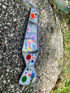 a colorful tie sitting on top of a rock next to a grass and dirt field