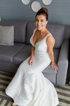 a woman sitting on top of a couch in a white dress and smiling at the camera