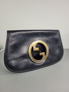 Add a touch of classic elegance to your outfit with this stunning vintage Gucci Blondie clutch bag. This is a vintage version of Gucci Blondie bag, that you can find in current Gucci collection. Crafted from high-quality black leather with gold-plated hardware, this medium-sized bag is perfect for any occasion, whether it's a wedding, party, or business event. The bag features a solid patternwith a bag width of 27 cm (10.6 cm), height of 17 cm (6.7"), and depth of 2.5 cm (1").   The interior is Gucci Blondie Bag, Gucci Collection, Business Event, Black Leather Clutch, Medium Sized Bags, Gucci Logo, Practical Bag, Leather Clutch Bag, Leather Clutch Bags