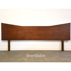 the headboard is made out of wood and has a long, curved design on it