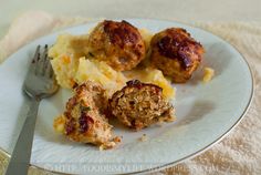 meatballs and mashed potatoes on a white plate with a fork next to it