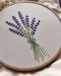 a close up of a embroidery on a piece of cloth with purple flowers in it