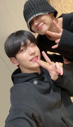 two young men posing for the camera with their fingers in the shape of peace signs