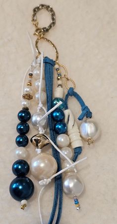 a blue and white necklace is hanging from a keychain with pearls on it