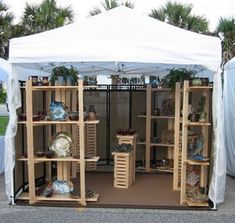 a white tent with wooden shelves filled with pots and pans