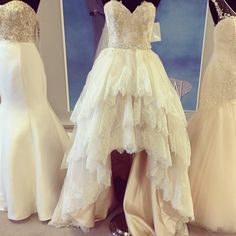 three wedding gowns on display in front of a mirror