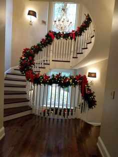 a staircase decorated for christmas with garland and poinsettis on the banister