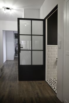 an empty room with white walls and black glass panels on the door, next to a wooden floor