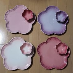 four pink and purple dishes on a wooden floor