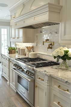 a white kitchen with marble counter tops and stainless steel stove top oven in the center