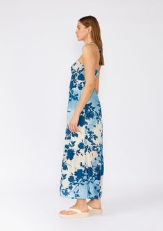 Get ready to turn heads with this stunning bohemian halter dress in a dreamy blue and white tropical floral print. The slim-fit smocked bodice provides a flattering silhouette, while the flowy maxi skirt with ruffle-trimmed tiered hemline adds a touch of whimsy. The sleeveless design and adjustable halter neck tie ensure a comfortable fit. Lined for added comfort, this dress is perfect for any summer occasion. Floral print Slim fit smocked bodice Flowy skirt Sleeveless Maxi length Ruffle-trimmed Summer Vacation Floral Dress With Smocked Bodice, Summer Floral Dress With Smocked Bodice For Vacation, Blue Flowy Halter Sundress, Breezy Floral Print Maxi Dress, Summer Floral Dress With Smocked Bodice For Beach, Blue Flowy Halter Dress For Spring, Halter Neck Floral Maxi Dress For Beach Season, Flowy Blue Halter Dress For Spring, Blue Floral Print Halter Dress For Vacation