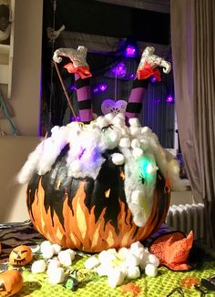 a decorated pumpkin with witches on it and other halloween decorations around the pumpkin, in front of a window