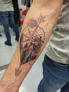 a man with a wolf and compass tattoo on his arm