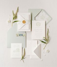 the wedding stationery is laid out on top of each other with flowers and foliage