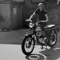 a man riding on the back of a motorcycle next to a brick building with windows