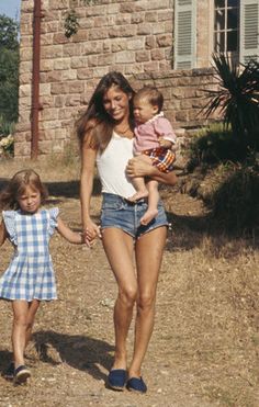 a woman holding hands with two small children