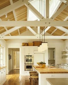 an open kitchen with white cabinets and wood flooring is pictured in this image, there are two stools on the counter