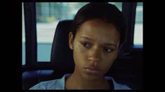 a woman sitting in the back seat of a car looking at the camera with an angry look on her face