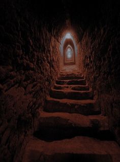 a dark tunnel with stairs leading up to the light