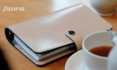 a white wallet sitting on top of a wooden table next to a cup of coffee