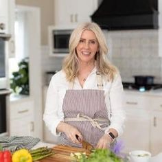 a woman standing in a kitchen preparing food on top of a wooden cutting board next to an oven