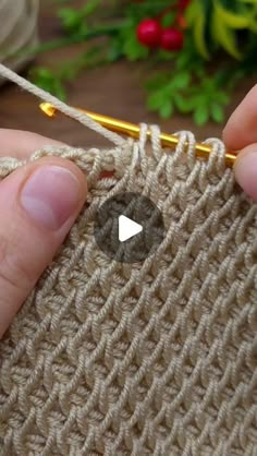 someone is crocheting the stitchs on a piece of cloth with a knitting needle