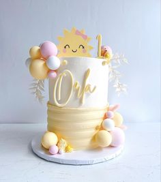 a white cake with yellow and pink decorations on it's top that says oh