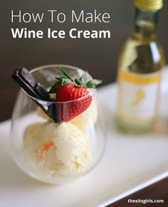 an ice cream sundae with strawberries in a glass on a tray next to a bottle of wine