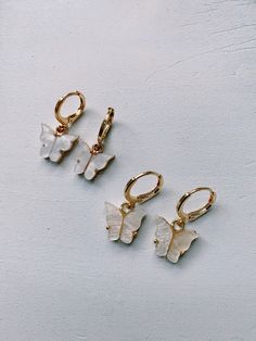 Elegant Pearlescent Butterfly Huggie Earrings. Hoops are made of gold plated brass, and each dainty butterfly charm is made of a pearlescent pewter acrylic, with a gold or rhodium backing. Cute Butterfly Jewelry For Pierced Ears, Dainty Butterfly Nickel-free Earrings, Dainty Nickel-free Butterfly Earrings, Dainty Nickel-free Butterfly Jewelry, Trendy Hoop Earrings With Butterfly Charm As Gift, Cute Gold Butterfly Jewelry, Cute Butterfly Gold Earrings, Trendy White Butterfly Jewelry, Nickel Free White Butterfly Earrings