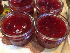 four jars filled with jam sitting on top of a table