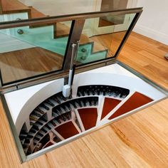 a spiral stair case with glass doors on the top and bottom floor, in front of a wooden floor