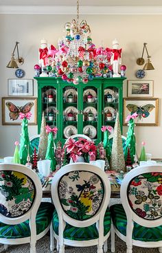 the dining room table is decorated with green and white chairs, an ornate china cabinet, and christmas decorations