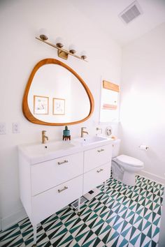 a bathroom with black and white checkered flooring, a large round mirror above the sink