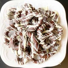 a white plate topped with chocolate covered pretzels and drizzled in white icing