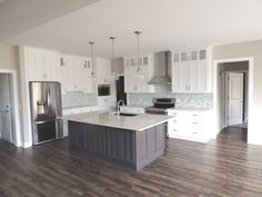 an empty kitchen with white cabinets and wood floors