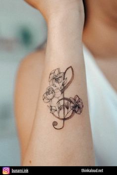 a woman with a tattoo on her arm has a musical note and flowers in it