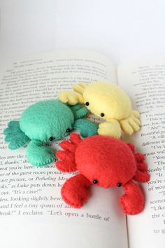 three stuffed animals sitting on top of an open book