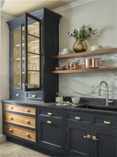 a kitchen with black cabinets and marble counter tops, gold pulls on the doors and brass knobs