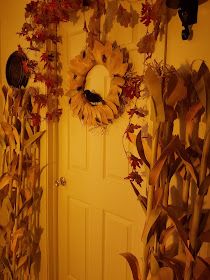 the door is decorated with sunflowers and corn stalks for fall decorations, along with two wreaths on either side of the door