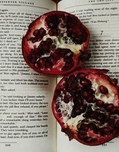 two pomegranates sitting on top of an open book next to each other