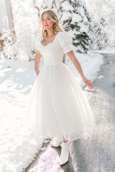 a woman in a white dress is standing in the snow