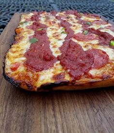 a pizza sitting on top of a wooden cutting board next to a fire hydrant