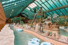 an indoor water park with large rocks and fake animals in the center, surrounded by greenery