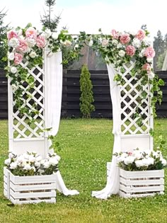 two white wooden planters with pink and white flowers on them sitting in the grass