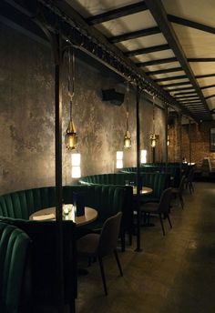 a dimly lit restaurant with green velvet booths