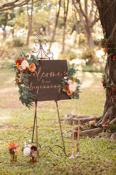 a sign that says welcome to the bride and groom in front of a tree with flowers